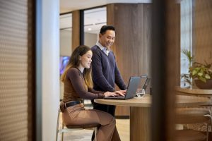 Two colleagues collaborating at a computer in an office.